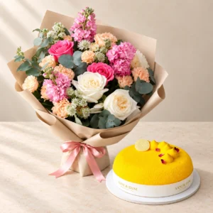 Pink, cream and peach Hues of Nature flowers beside a small yellow Aani & Dani Mango Cake