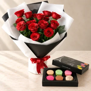 Eternal Love red roses in black and white wrapping beside a box of six assorted macarons